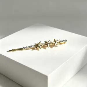 Close-up of golden star hair clip with glittering rhinestones on a white pedestal