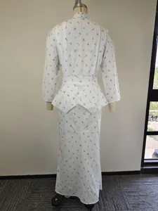 Vista posteriore di un elegante abito lungo bianco a fiori blu con maniche lunghe