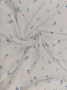 Dettaglio ravvicinato di tessuto bianco leggero con eleganti motivi floreali blu