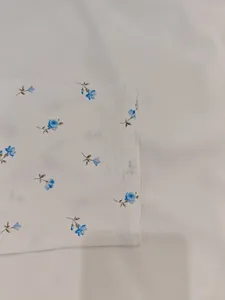 Dettaglio macro di un elegante motivo floreale blu su tessuto di abito primaverile bianco