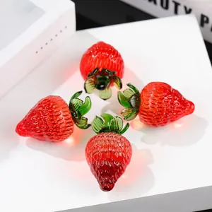 Detailed close-up of four realistic red crystal glass strawberry ornaments with green leaves