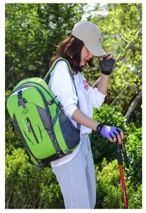 A young woman wearing a large green outdoor hiking backpack with a red trekking pole
