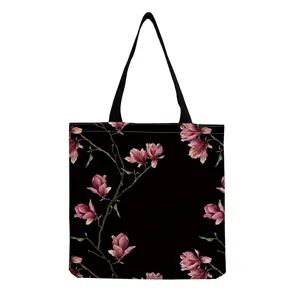 Detailed close-up showing the realistic pink magnolia floral print on a black tote bag