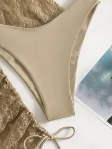 Dettaglio dell'insieme bikini beige in pizzo a vita alta con delicati lacci laterali