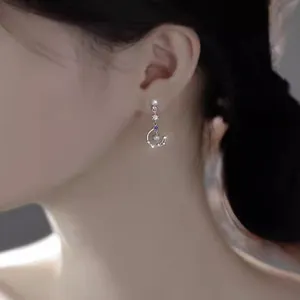 Close-up view of elegant star and moon moonstone tassel earrings worn on a model's ear