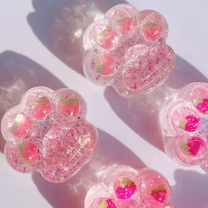 Pink cat paw jelly squishy toy with glitter and strawberry inclusions on white background