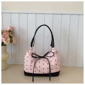 Detailed view of the pink textured underarm bag with elegant black bow-tie accents