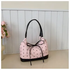 Detailed view of pink bow underarm bag with textured fabric and stylish black accents
