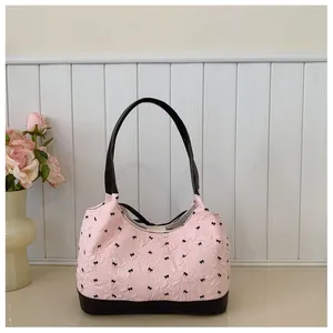 Detail view of pink textured underarm bag with black bow pattern and black straps.