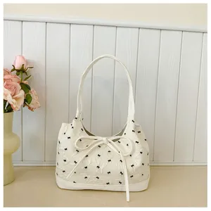 Close-up detail of a white Korean-style shoulder bag with elegant black bow patterns