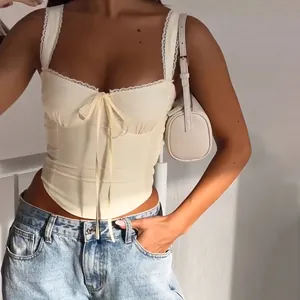 Detail view of slim fit cream bustier top featuring elegant white lace trim and bow knot