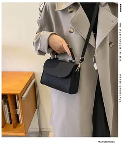 Elegant black snake pattern felt small square bag worn with a stylish trench coat