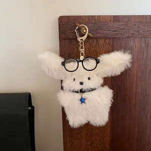 Close-up of a white plush rabbit keychain with glasses and a blue star charm