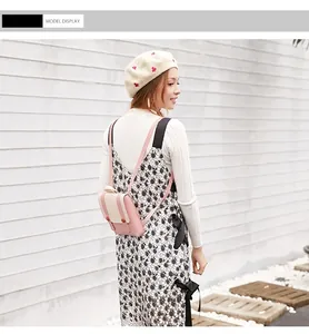 Detail view of a mini pink and white backpack worn by a model in a casual outfit.