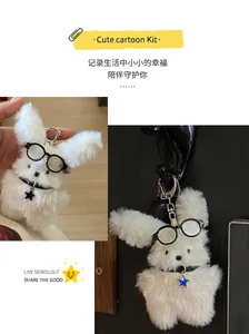 Close-up of white fluffy rabbit plush keychain with round glasses and star charm
