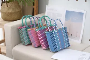 Colorful woven plastic tote bags with contrast patterns displayed on a sofa