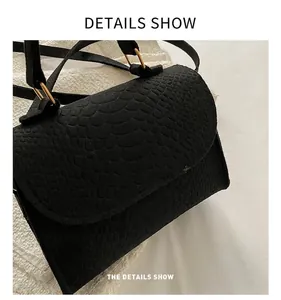 Detail shot of black snake-pattern embossed felt fabric on small square handbag