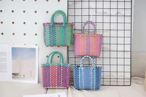 Detailed view of four colorful hand-woven plastic tote baskets hanging on a display wall