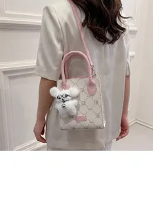 Close-up of a cute white plush bunny keychain with pilot glasses on a handbag.