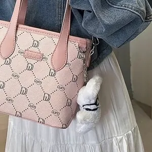 Detail view of a white fluffy pilot rabbit plushie hanging on a pink patterned fashion bag