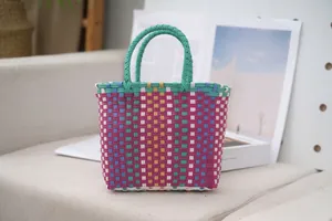 Detail view of a colorful plastic woven tote bag with a vibrant geometric pattern.