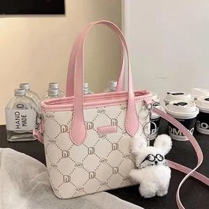 Detailed shot of a cute white plush rabbit pendant with glasses on a pink patterned bag