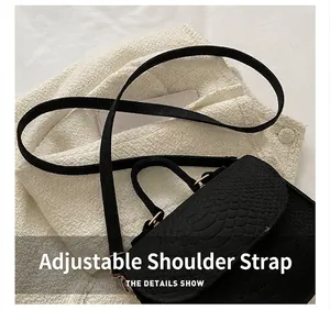 Detail of the adjustable shoulder strap and snake pattern texture on a black crossbody bag