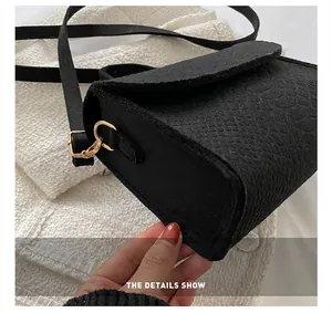 Close-up of black felt small square bag featuring realistic snake pattern texture detail