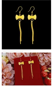 Macro detail view of elegant gold-tone long tassel earrings featuring a delicate bowknot design.