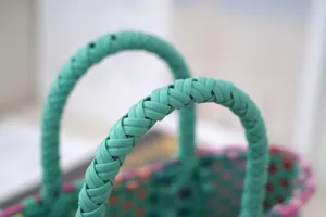Macro view of the mint green braided handle on a colorful woven plastic shopper bag
