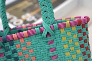 Close-up of colorful plastic woven tote bag showing handle and texture
