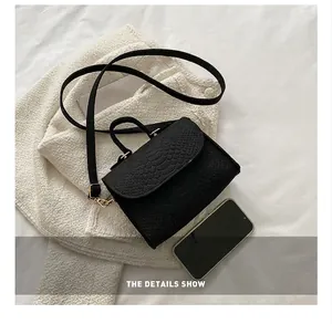 Detailed view of black felt snake skin pattern handbag with size comparison to smartphone