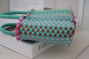 Close-up of colorful hand-woven plastic tote bag featuring a vibrant striped pattern design