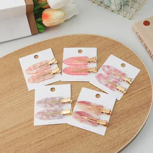 Set of two elegant sakura pink marble patterned seamless hair clips on a wooden tray