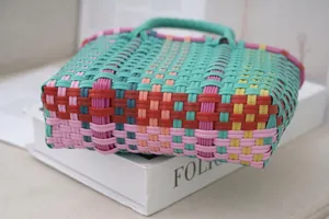 Close-up of a colorful woven plastic tote bag with vibrant multi-color contrast design.