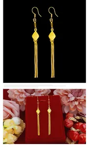 Detail view of long gold tassel hook earrings on black and floral backgrounds.