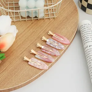 Set of five pink marble pattern hair clips for girls on a wooden tray with flowers