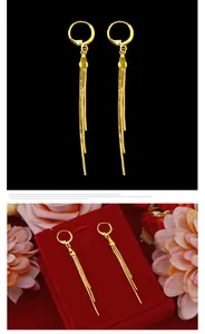 Detailed macro view of elegant gold long tassel earrings displayed on a luxury red gift box