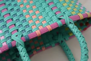 Detailed macro shot showing the vibrant colorful woven plastic texture of a handmade tote bag