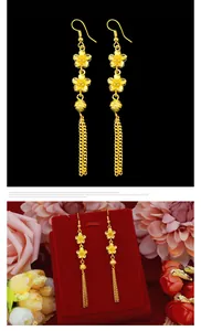 Detailed view of gold flower tassel earrings on a red display stand