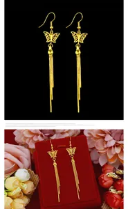 Detailed view of golden butterfly tassel earrings on a red display stand with flowers.