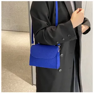 Model wearing vibrant blue snake-textured felt crossbody square bag with black coat