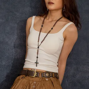 Close-up of a long wooden bead rosary necklace with a metal cross pendant on model.