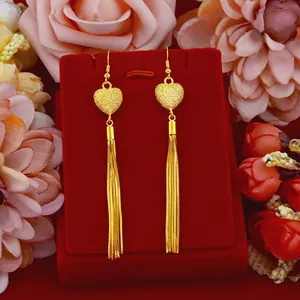 Elegant gold-toned heart tassel earrings on a red jewelry display box with roses.