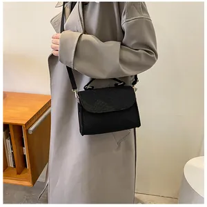 Close-up of a black snake-patterned felt crossbody bag worn with a grey trench coat
