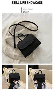 Detail shot of a black snakeskin pattern felt handbag displayed on white clothing