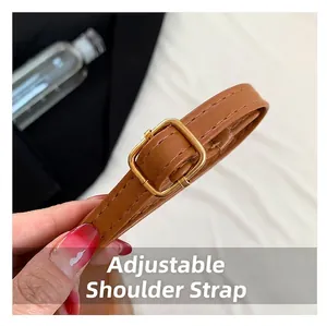 Close-up of an adjustable brown leather shoulder strap featuring a gold-tone metal buckle