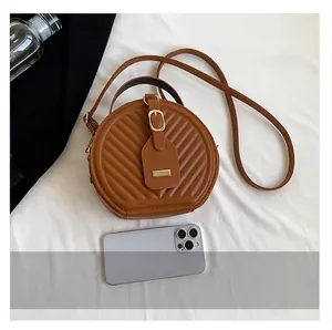 Size comparison of the stylish brown quilted round crossbody bag shown with a smartphone