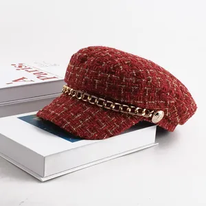Detailed view of a vintage red tweed newsboy cap with gold chain and decorative buttons