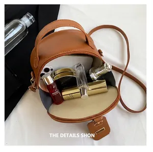 Interior view of a small brown round bag displaying capacity for cosmetics and phone